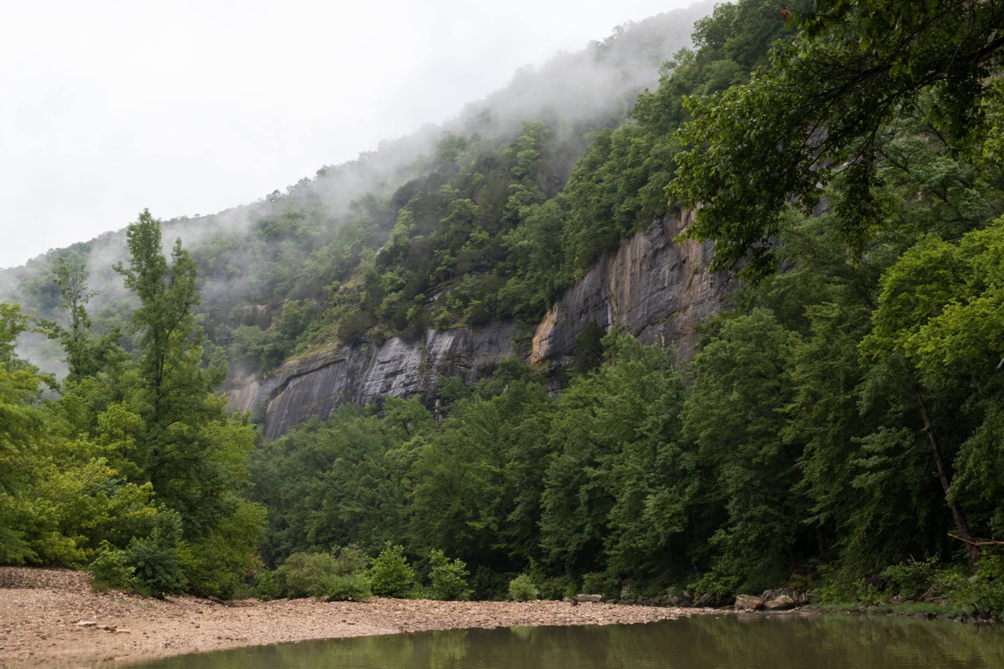 A limestone bluff rising out of fog above a gravel bar on the Buffalo National River.