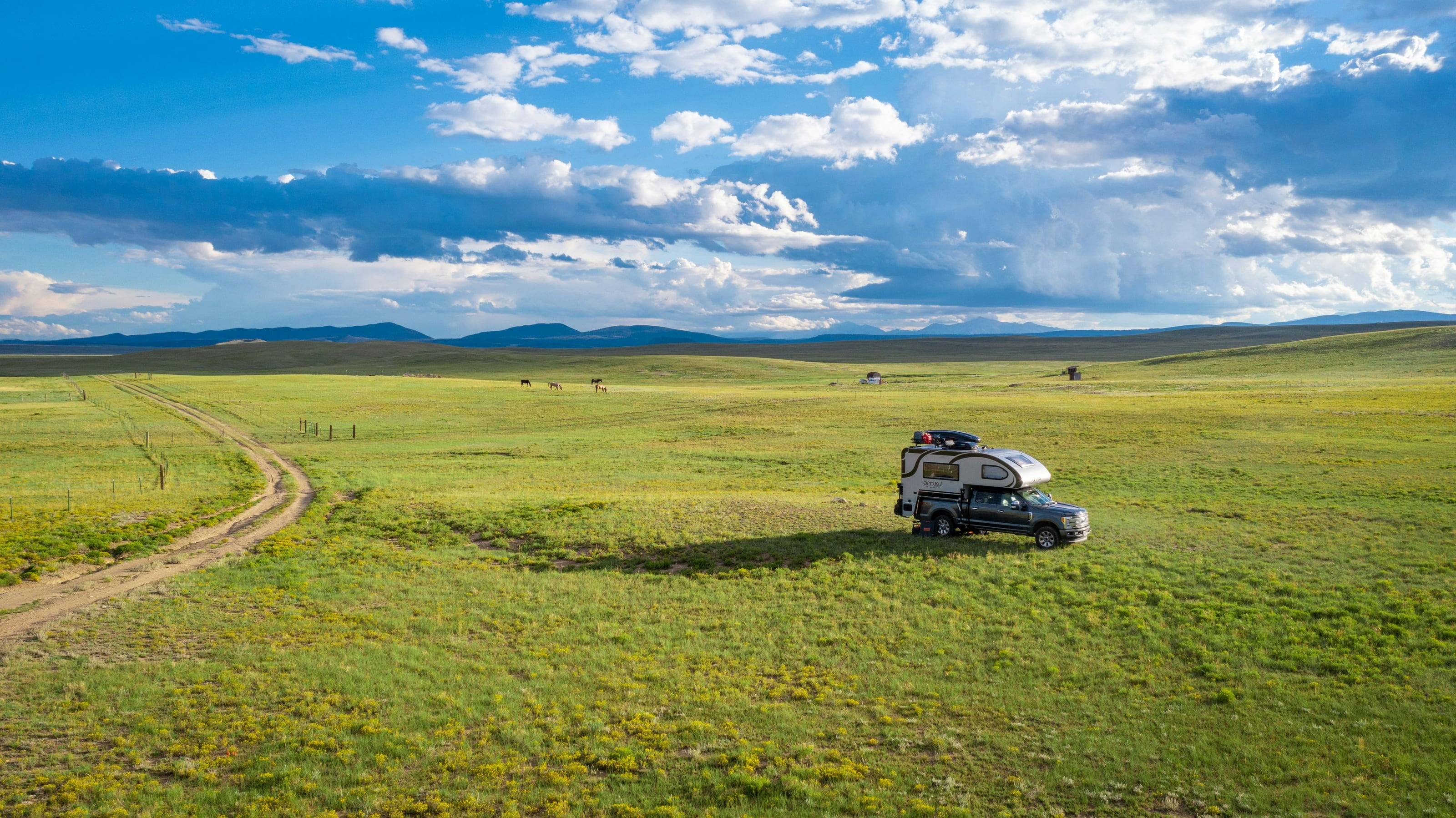 A 4x4 with a roof tent parked off a two-track in open grassland under a big sky.